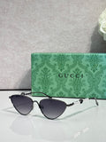 Gucci cat-eye sunglasses with dark lenses and black frames, gold-tone hinges