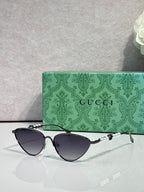 Gucci cat-eye sunglasses with dark lenses and black frames, gold-tone hinges