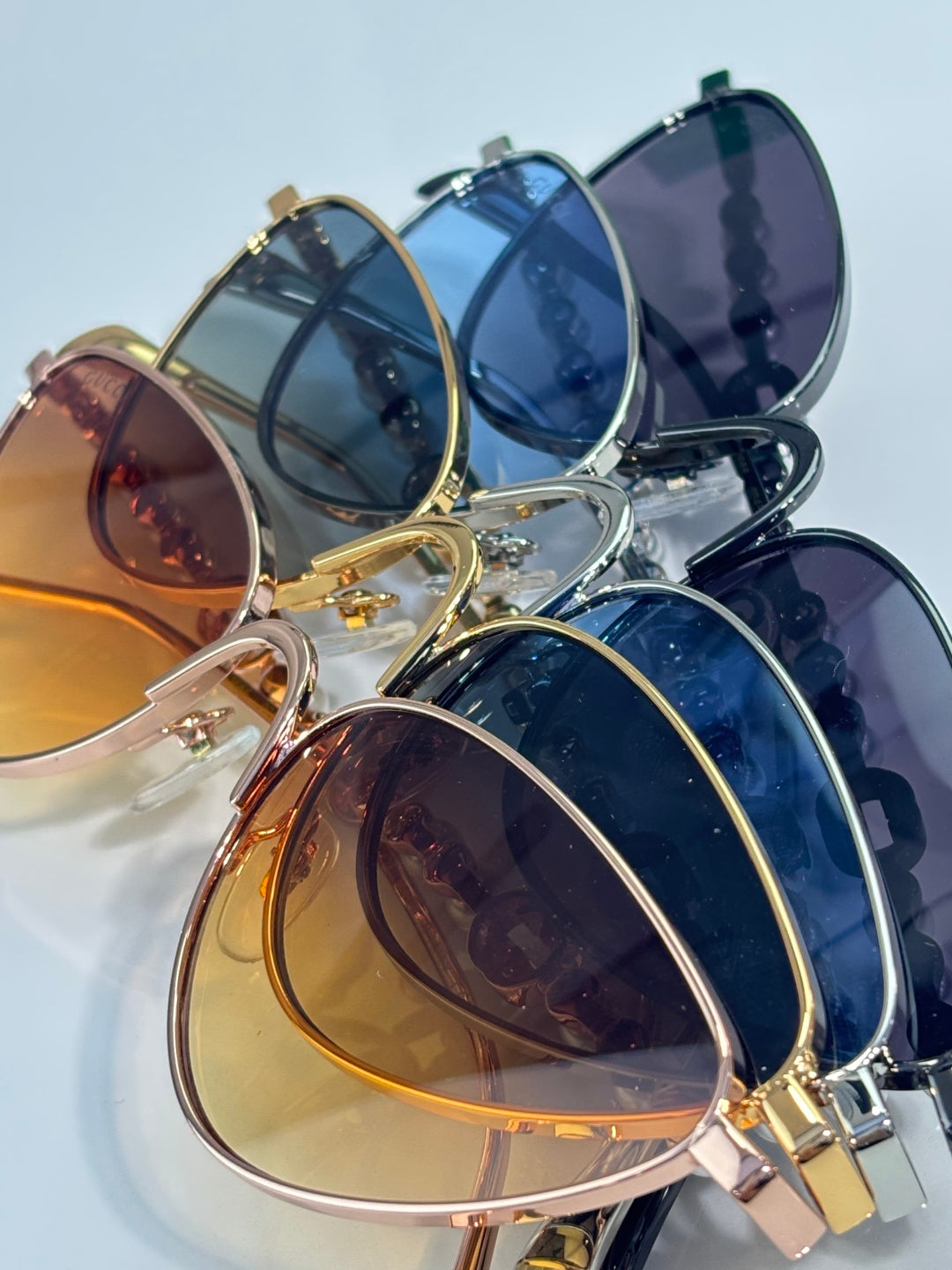 Gucci sunglasses stack: gold-tone frames with amber and blue tinted lenses