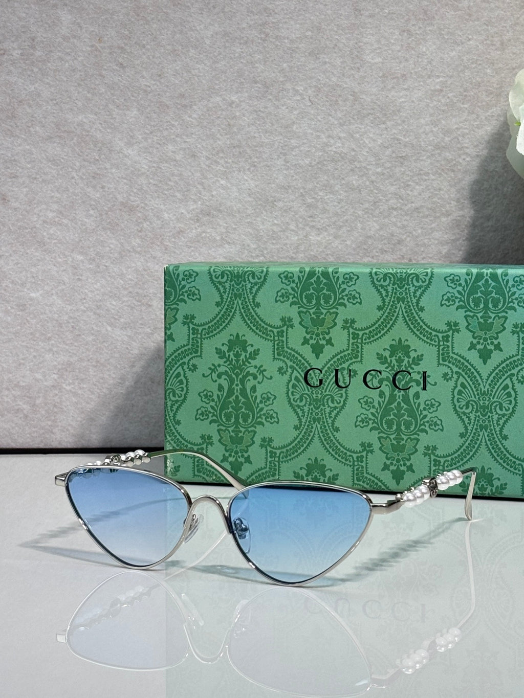 Gucci cat-eye sunglasses with light blue lenses and silver-tone frames, chain arms