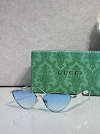 Gucci cat-eye sunglasses with light blue lenses and silver-tone frames, chain arms
