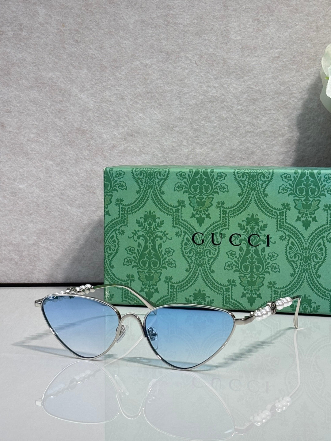 Gucci cat-eye sunglasses with light blue lenses and silver-tone frames, chain arms
