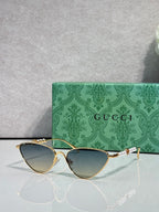 Gucci cat-eye sunglasses with blue-gray lenses and gold-tone frames, side bow detail