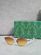 Gucci cat-eye sunglasses with amber lenses and gold-tone frames, thin chain arms