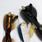 Bvlgari sunglasses close-up: black lenses, gold-toned frame, and gold emblem detail.