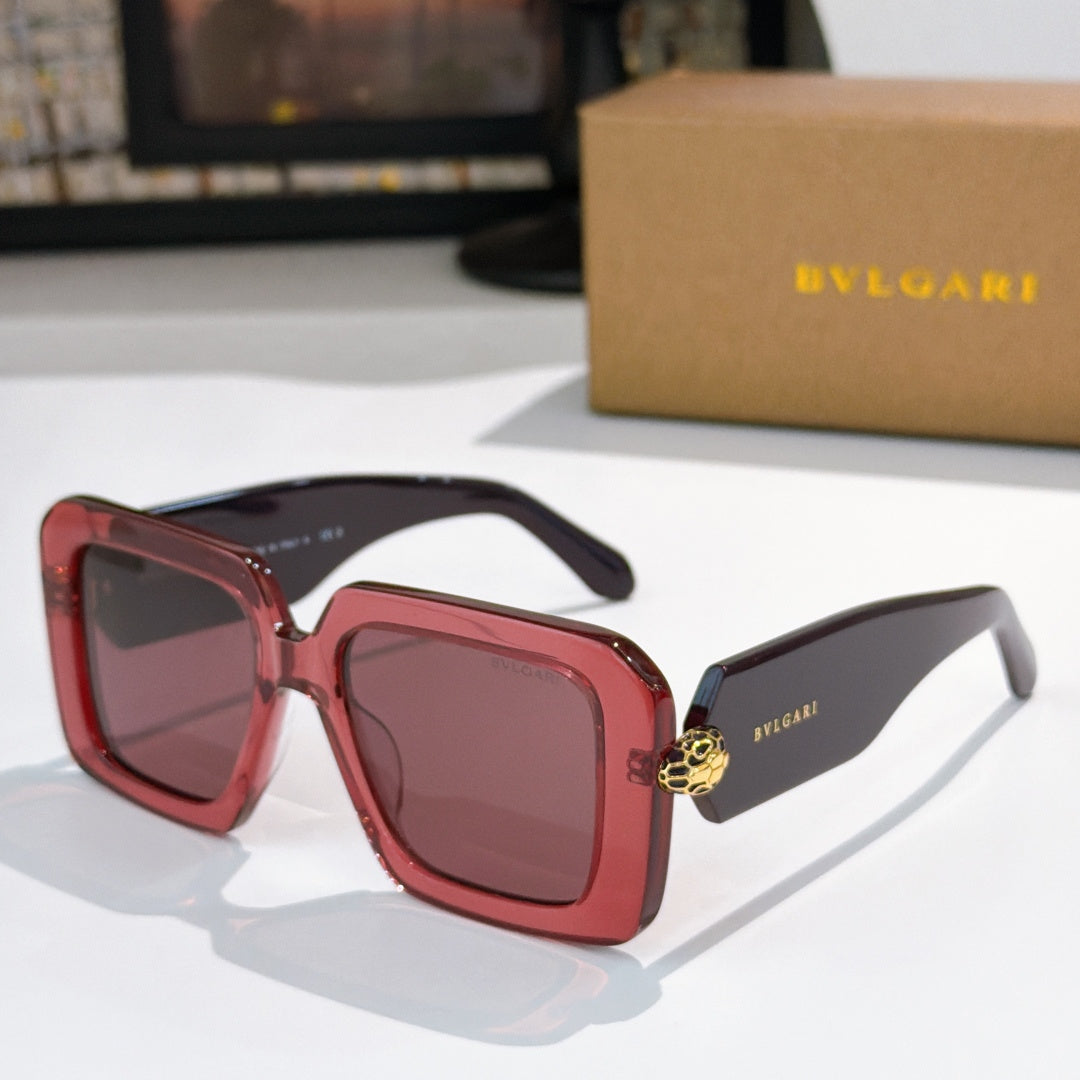 Square sunglasses, red frames with dark lenses, gold logo on temples