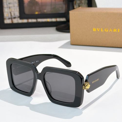 Square sunglasses, black frames with dark lenses, gold logo on temples