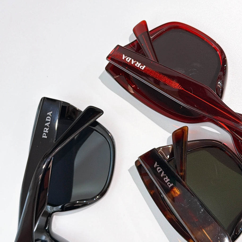 Stacked Prada sunglasses, red and dark frames with tinted lenses