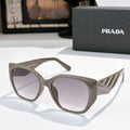 Prada cat-eye sunglasses with dark lenses and olive-tinted translucent frames