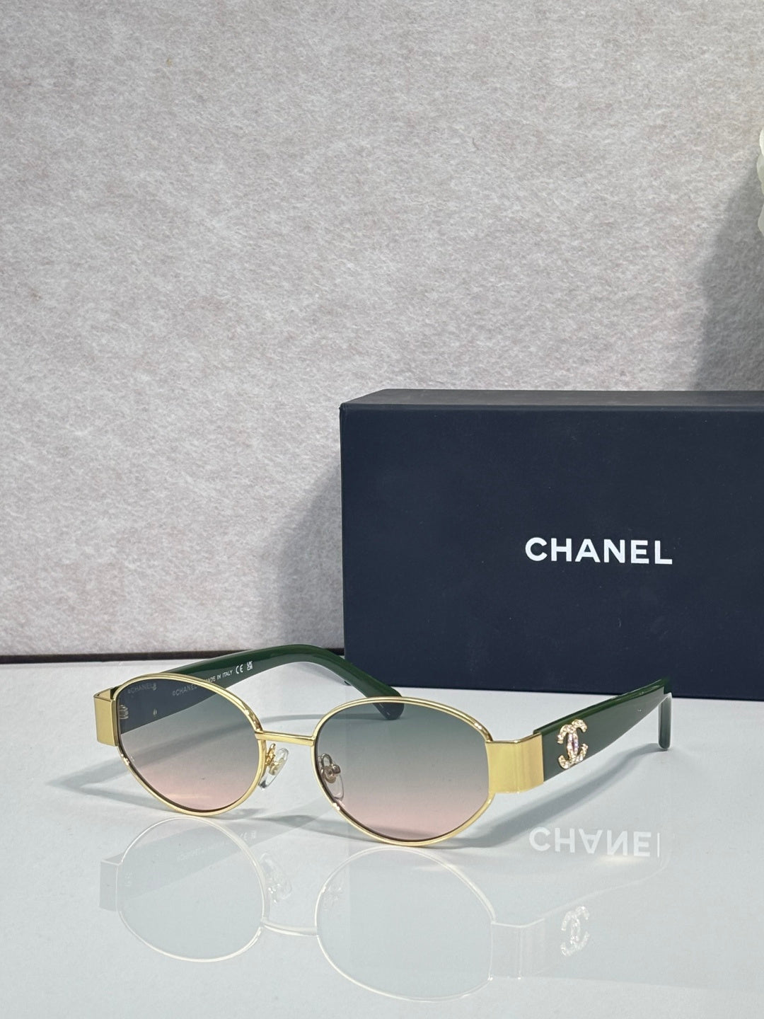 CHANEL sunglasses with gold frame, green temples, tinted rose lenses.