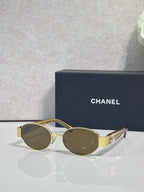 CHANEL sunglasses with gold frame, tinted dark lenses, wide metal temples.