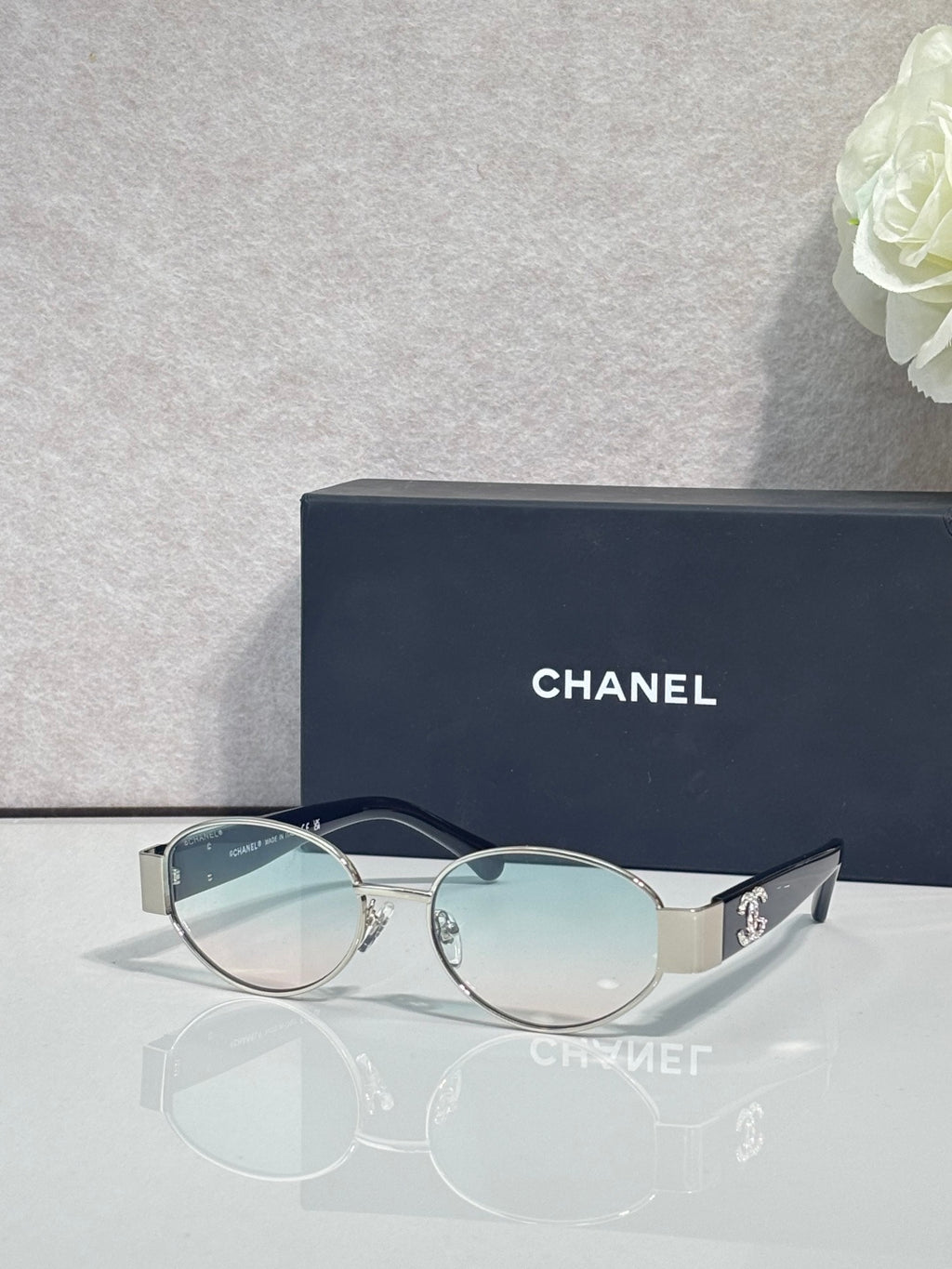 CHANEL sunglasses with gold frame, light blue lenses, metal temple arms.