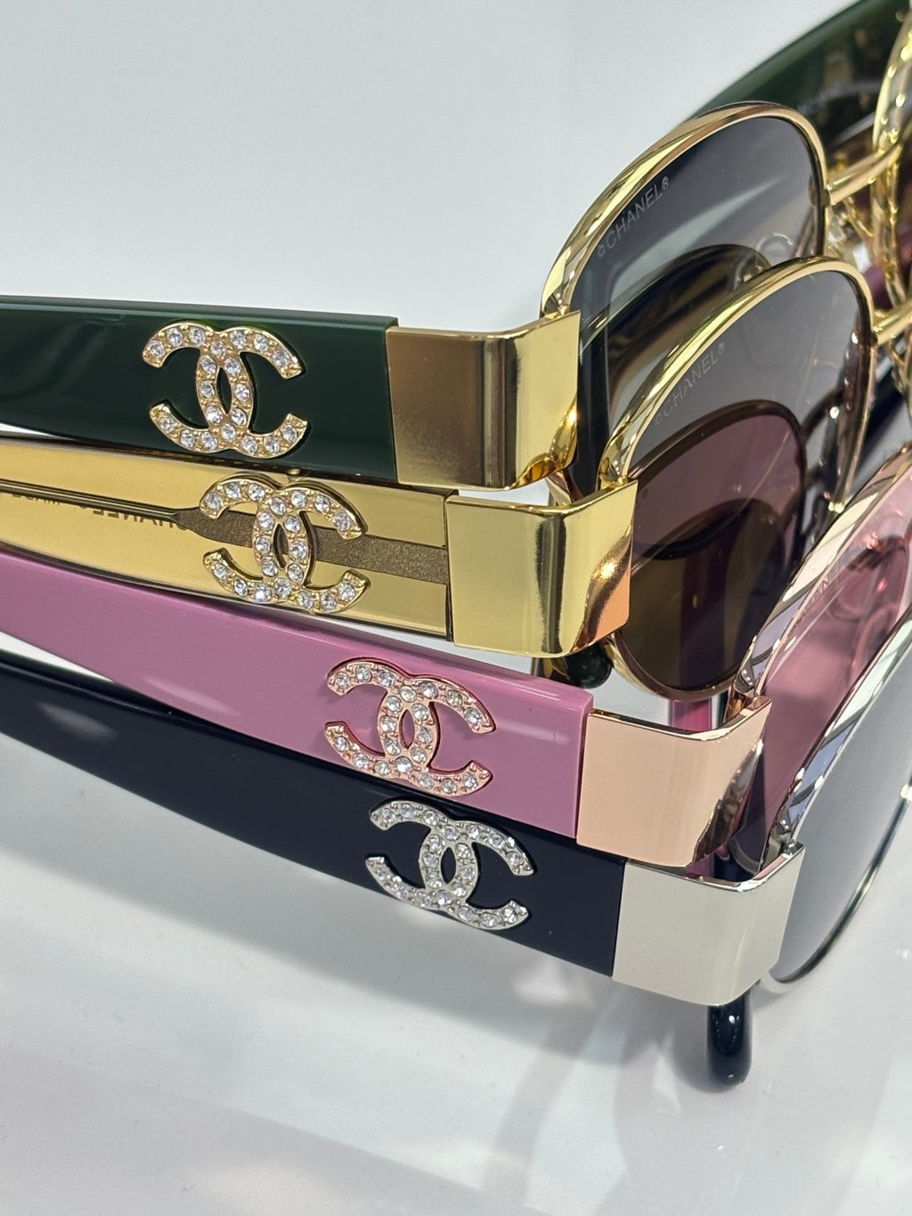 CHANEL sunglasses with gold frames and dark lenses; CC logo on case lids.