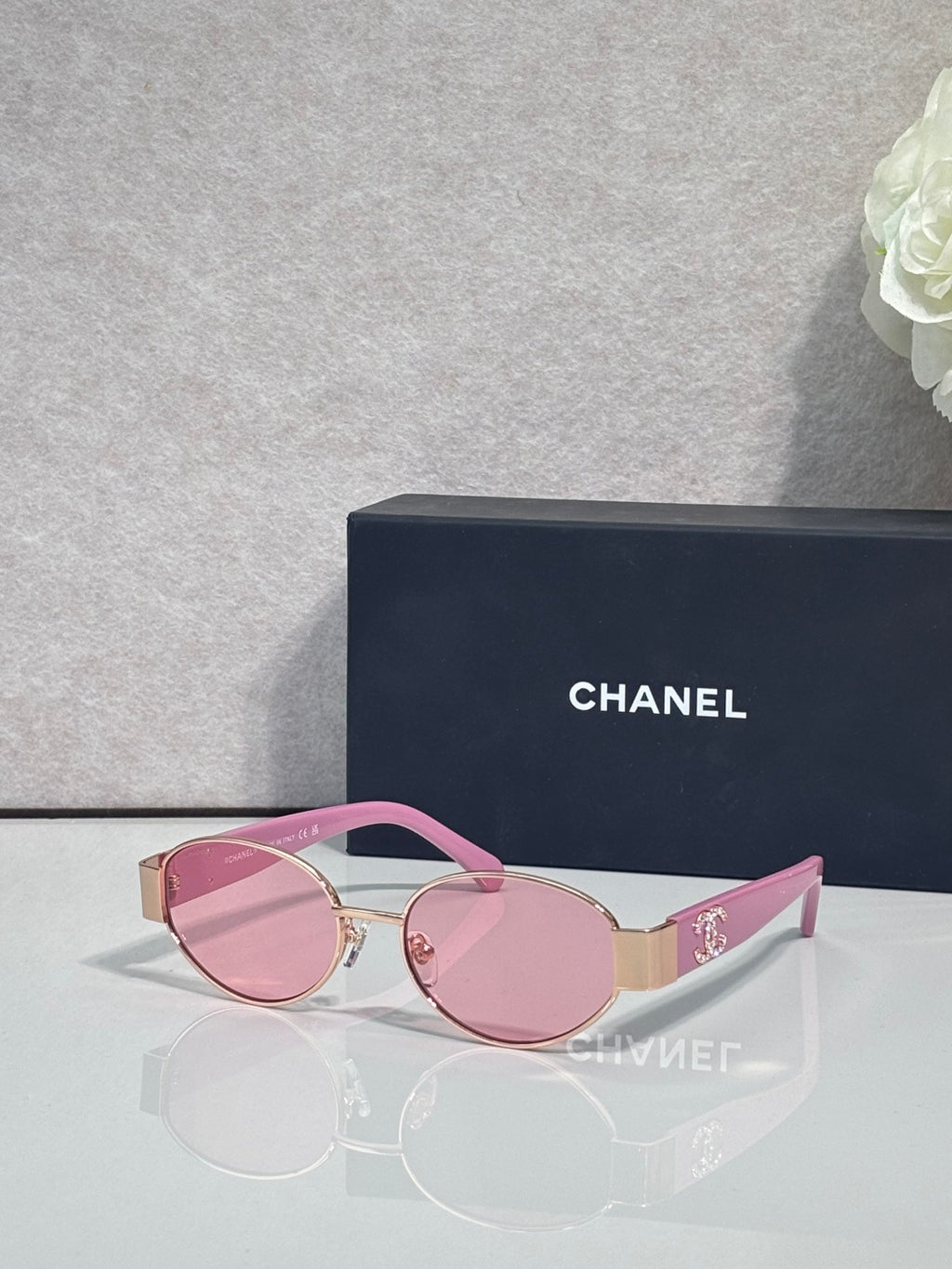 CHANEL sunglasses with gold frame, pink temples, tinted pink lenses.