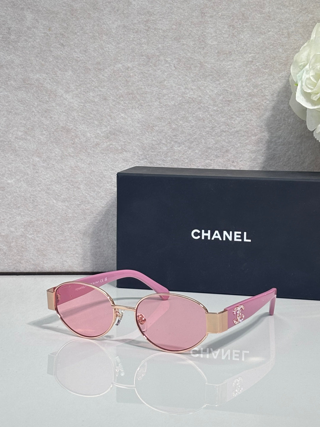 CHANEL sunglasses with gold frame, pink temples, tinted pink lenses.