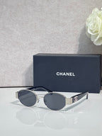 CHANEL sunglasses with gold frame, dark lenses, metal temple arms and tips.