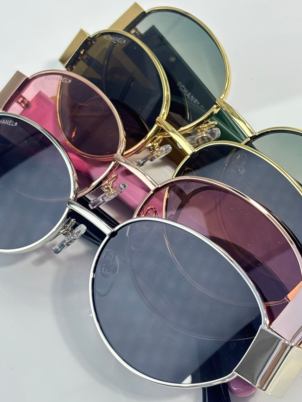 CHANEL sunglasses assortment with gold frames and round tinted lenses in pink and navy.