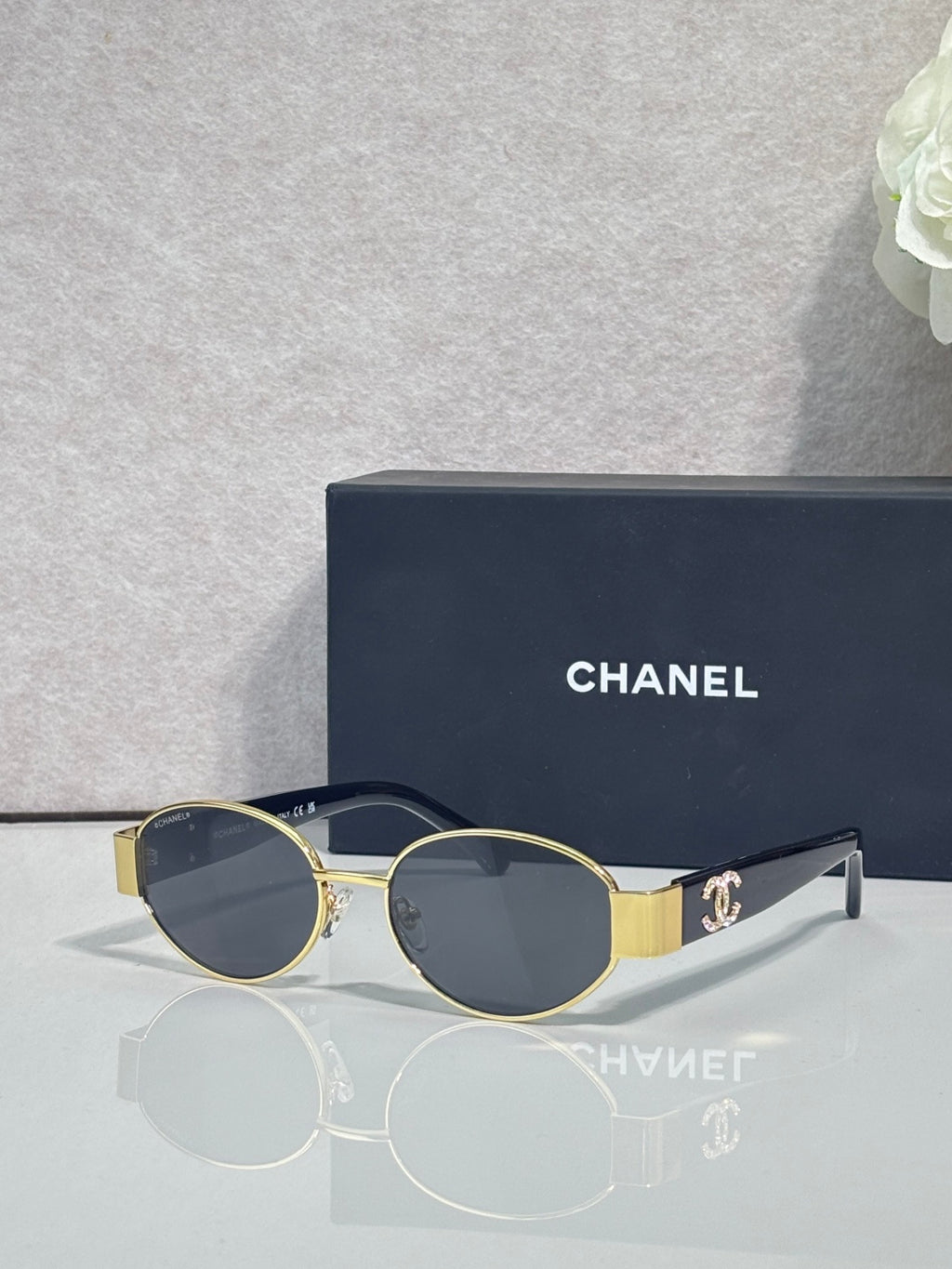 CHANEL sunglasses with gold frame, dark lenses, black temple tips.