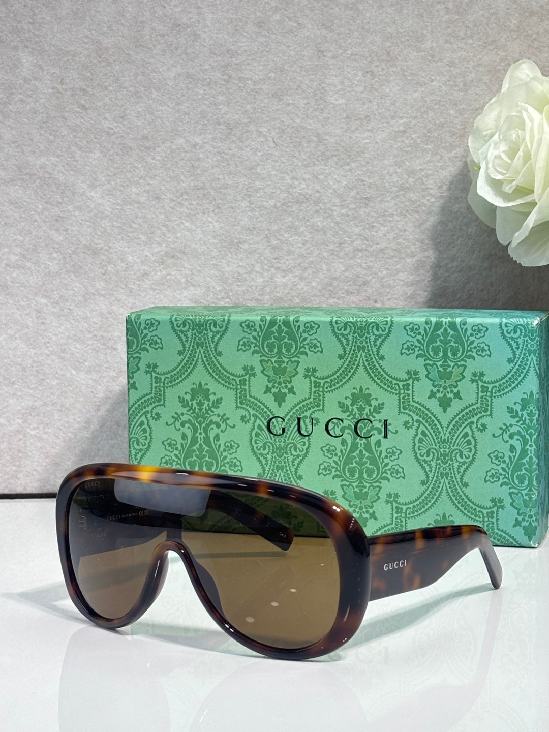 Gucci oversized sunglasses with tortoiseshell frame and dark lenses, on green logo case