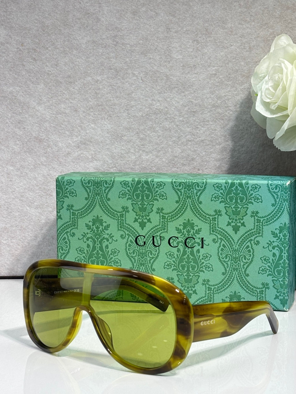 Gucci oversized sunglasses with olive/yellow tortoiseshell frame and amber lenses, case behind