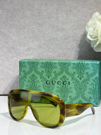 Gucci oversized sunglasses with olive/yellow tortoiseshell frame and amber lenses, case behind