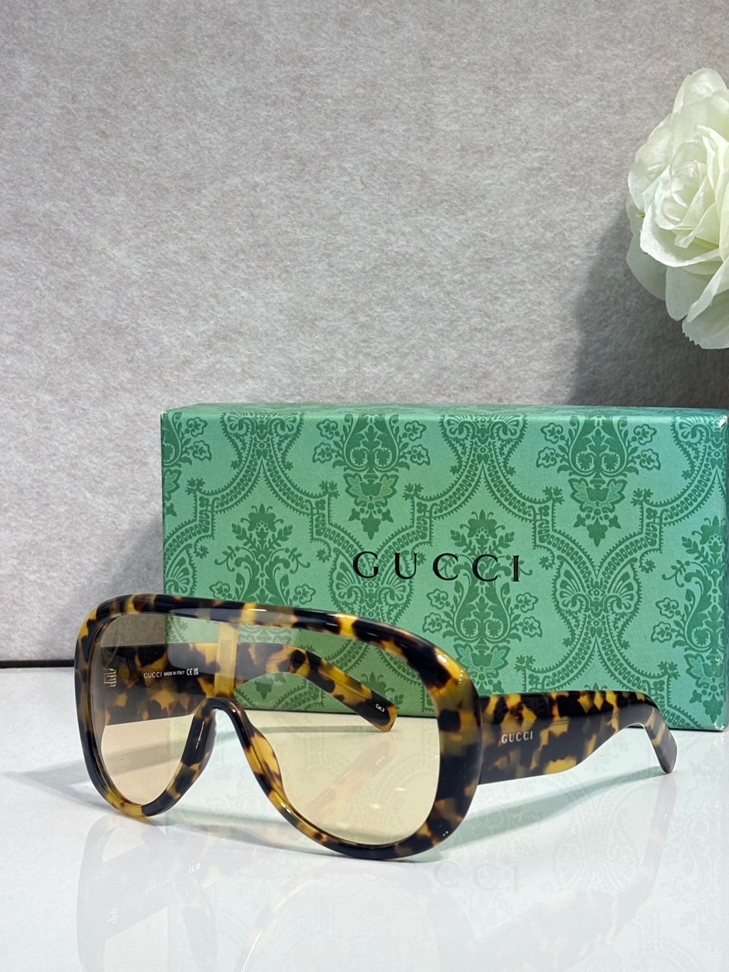 Gucci oversized sunglasses with yellow tortoiseshell frame and amber-tinted lenses, case behind