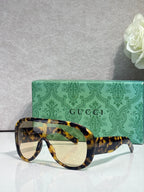 Gucci oversized sunglasses with yellow tortoiseshell frame and amber-tinted lenses, case behind