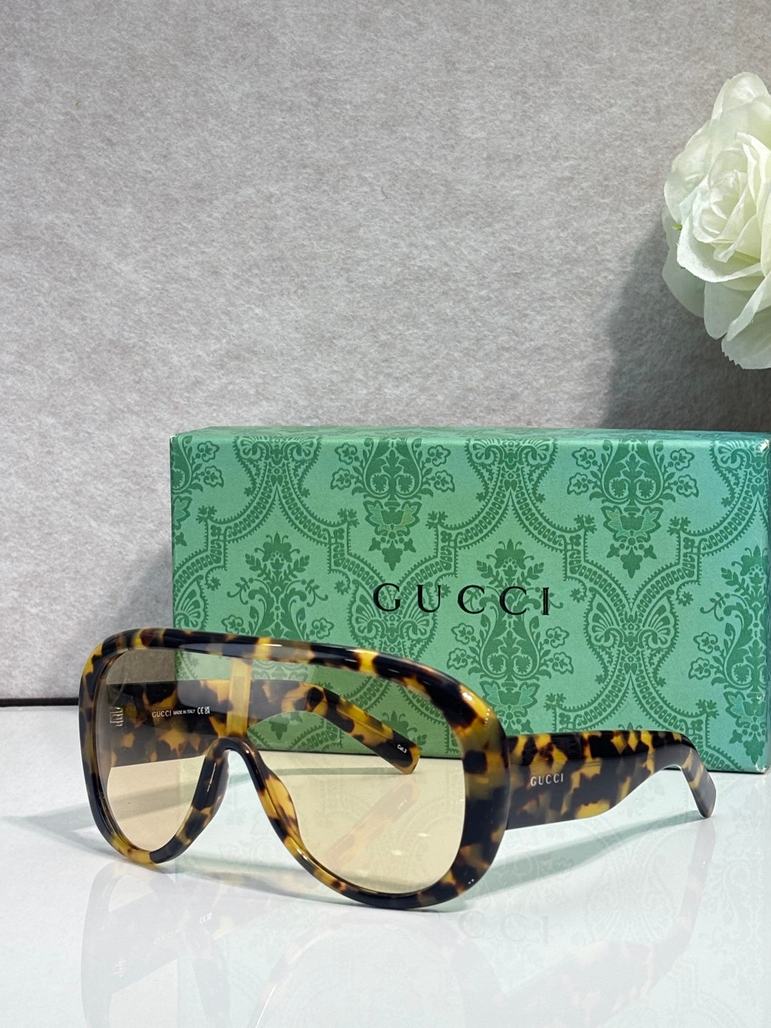 Gucci oversized sunglasses with yellow tortoiseshell frame and amber-tinted lenses, case behind