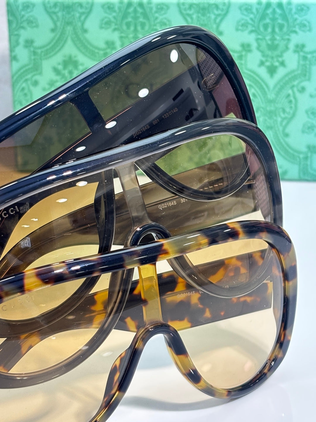 Gucci sunglasses close-up: oval tinted lenses, dark navy frame with tortoiseshell accents