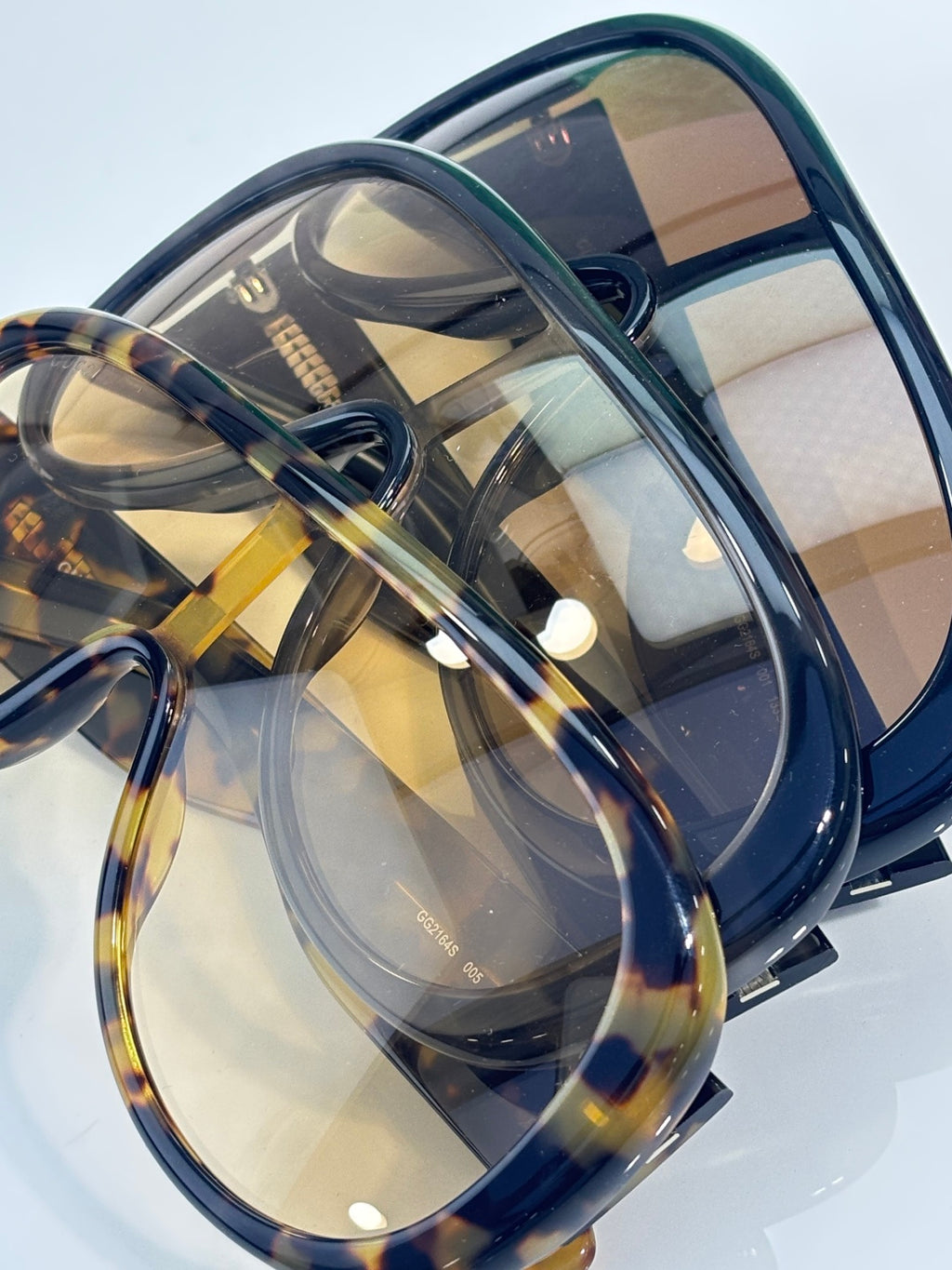 Gucci oval sunglasses close-up with navy frame and amber-tinted lenses, tortoiseshell detail