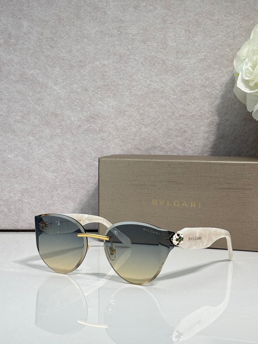 Bvlgari sunglasses with pale gold frame and blue-tinted gradient lenses, white temples