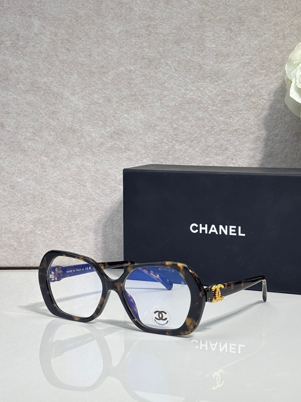Eyeglasses with dark tortoiseshell frame, blue lenses, CHANEL logo on temple