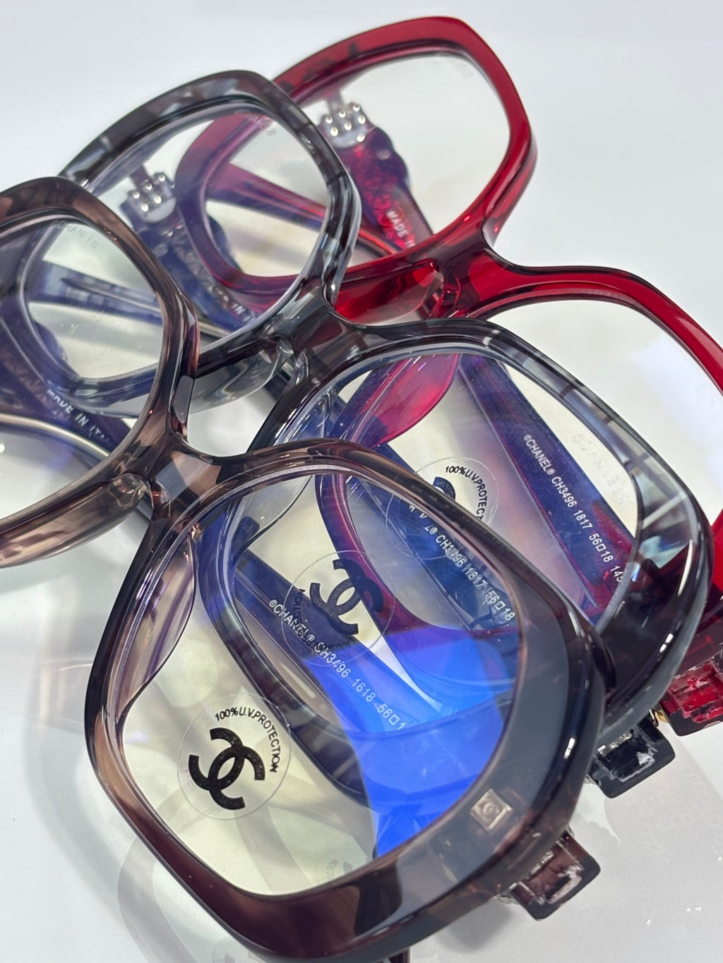 Close-up eyeglasses set with red and purple frames, blue lenses, CHANEL logo