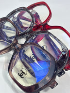 Close-up eyeglasses set with red and purple frames, blue lenses, CHANEL logo