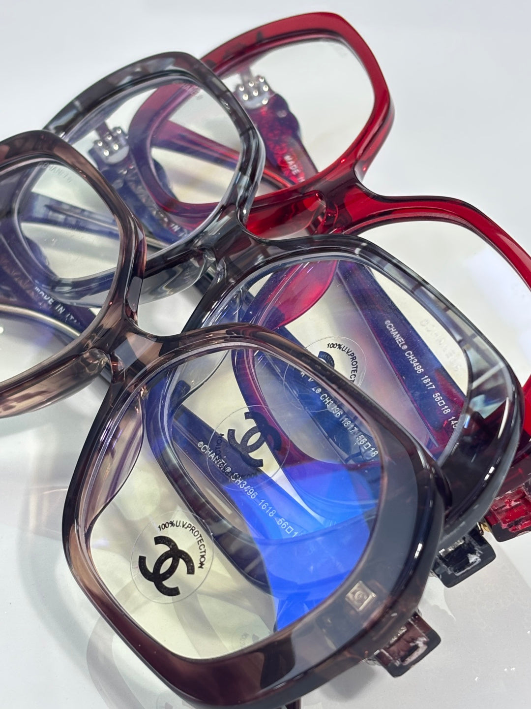 Close-up eyeglasses set with red and purple frames, blue lenses, CHANEL logo
