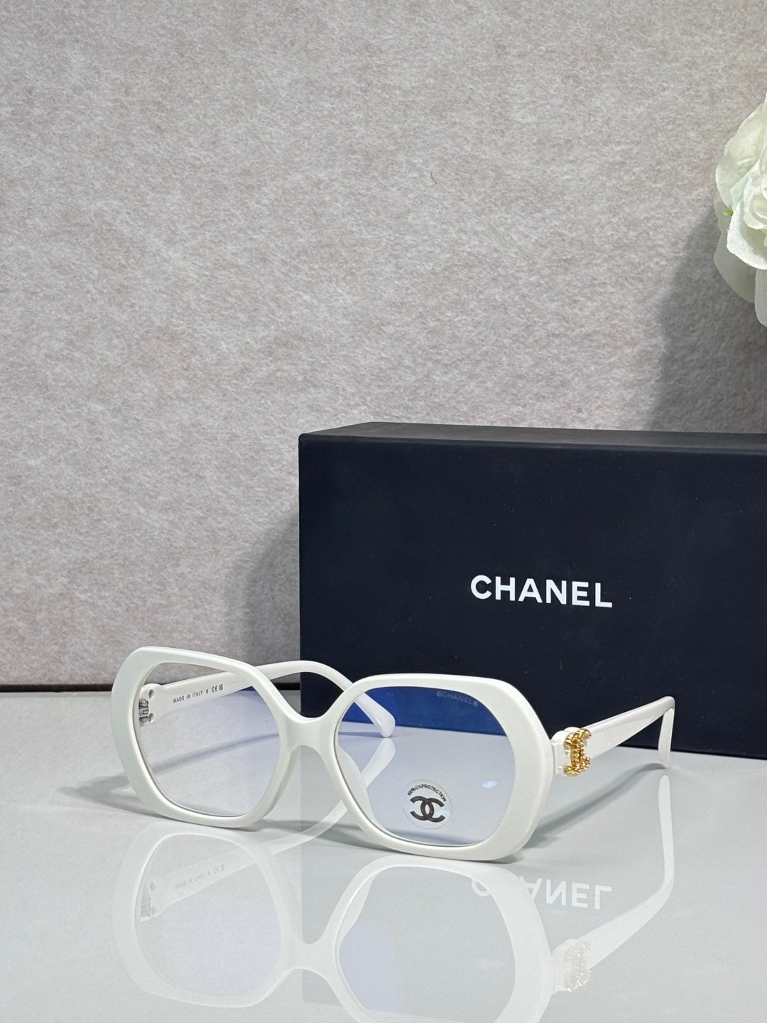 Eyeglasses with white frame, blue lenses, CHANEL logo on temple