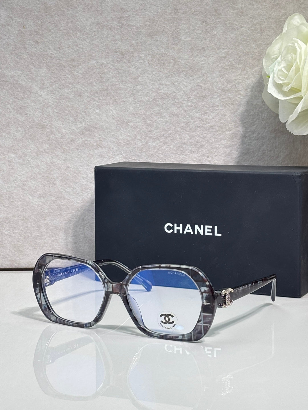 Eyeglasses with dark purple frame, blue lenses, CHANEL logo on temple