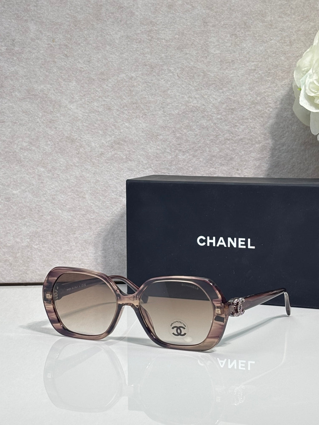 Chanel burgundy square sunglasses with gold-toned logo on the temple and tinted lenses.