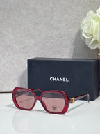 Chanel red square sunglasses with logo on the lens and gold-toned temple accents.