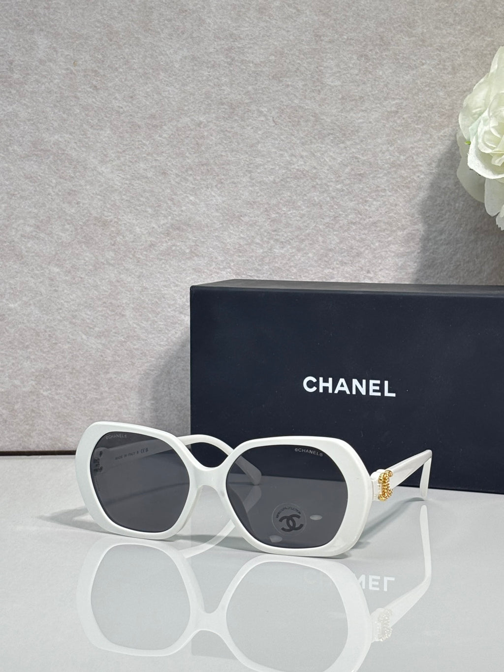 Chanel white round sunglasses with logo on the lens and gold-toned temple accents.