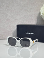 Chanel white round sunglasses with logo on the lens and gold-toned temple accents.