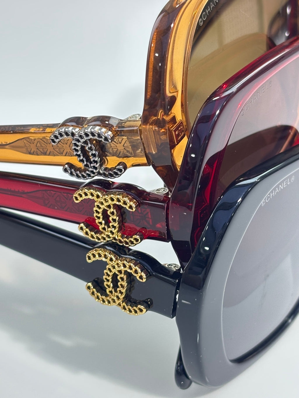 Chanel sunglasses temple close-up with gold chain and eagle-style emblem detail.