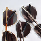 Stacked sunglasses with metal frames and dark lenses, close-up