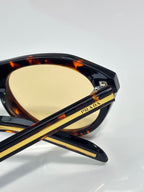 Tortoiseshell Prada sunglasses with yellow lenses and gold temple stripes