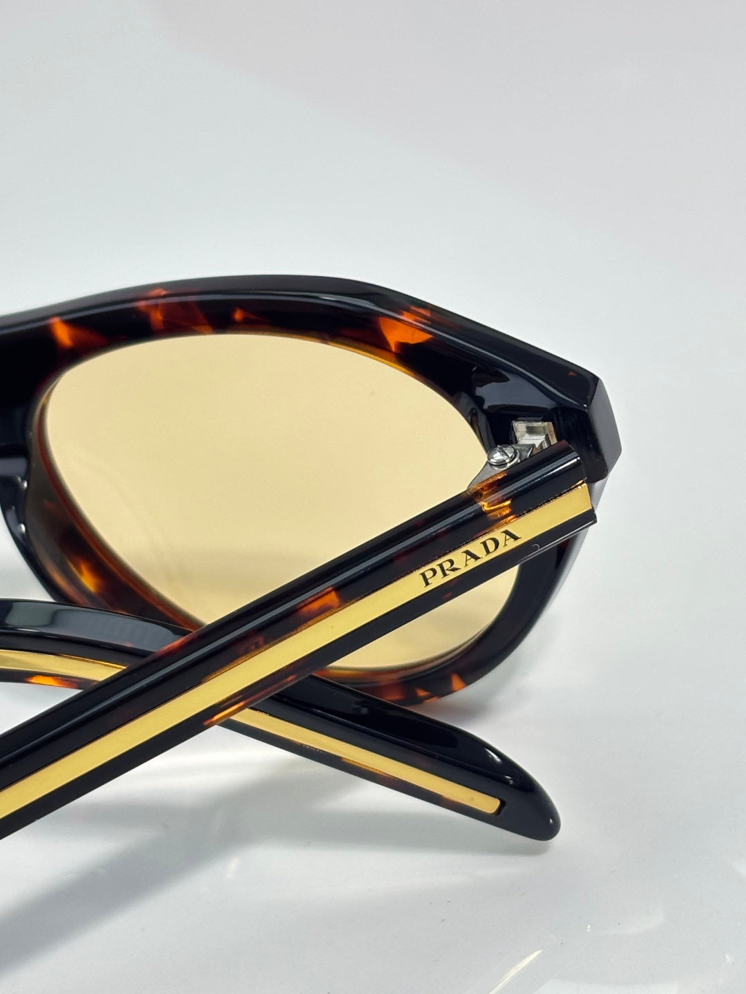 Tortoiseshell Prada sunglasses with yellow lenses and gold temple stripes