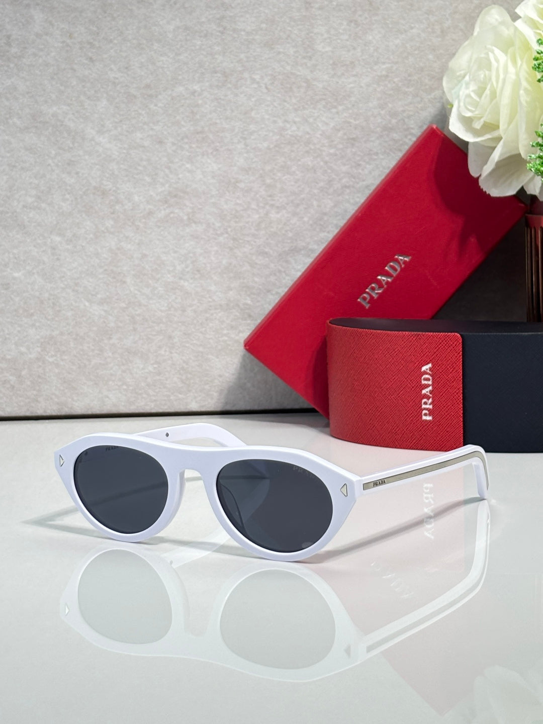 White Prada sunglasses with dark round lenses and thick plastic frame