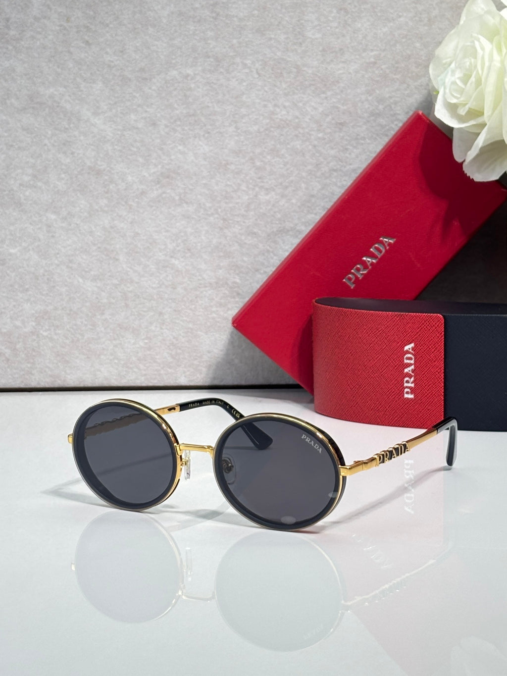 Prada round sunglasses with black lenses and gold-tone metal frame, black temples