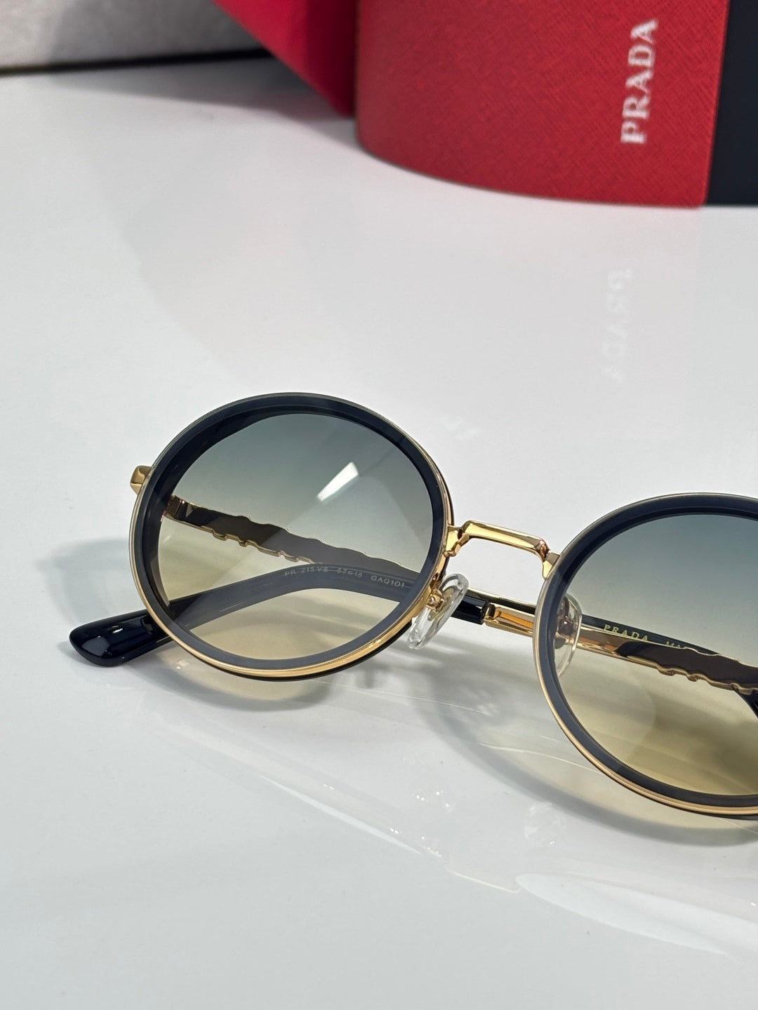 Prada round sunglasses close-up with gold-tone frame and reflective dark lenses