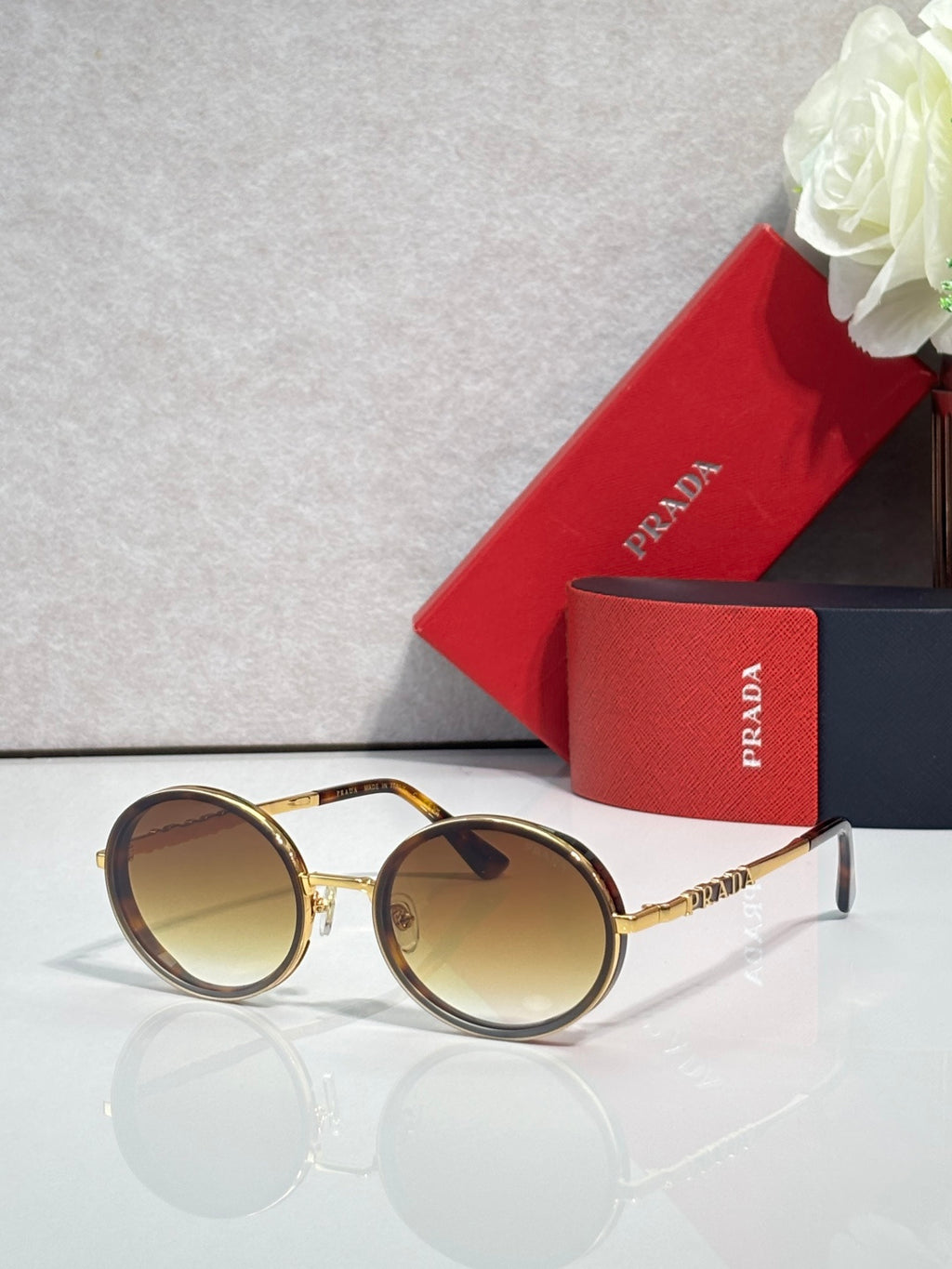 Prada round sunglasses with gold-tone frame and amber-tinted lenses, tortoise arms