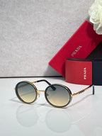 Prada round sunglasses with tinted lenses and gold-tone metal frame, black accents